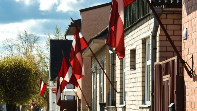 Latvijas karogi karogturētājos pie dzīvojamām mājām